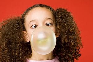 Little girl blows bubble gum bubble