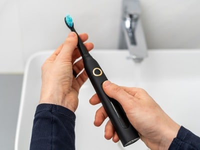a man holding a black electric toothbrush over the sink