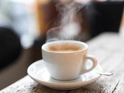 a cup of coffee with visible steam sitting on top of a coffee table