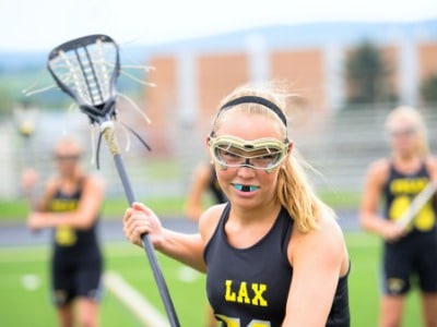 a female student playing lacrosse with an orthodontic mouth guard