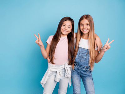 Two girls with braces posing for a photo on a blue background.