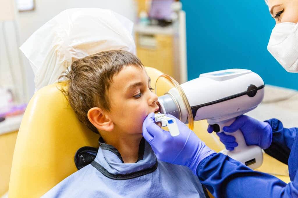 A young boy is being examined by an orthodontist.