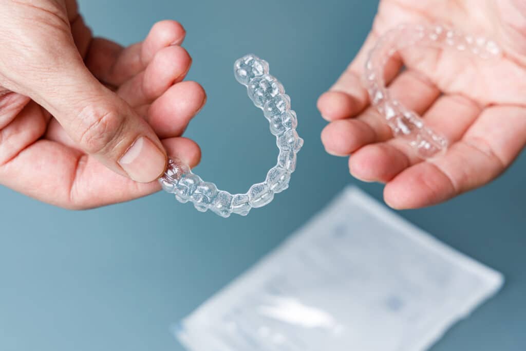 A person holding a pair of clear aligners.