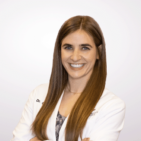 Dr. George, a smiling female orthodontist in a white coat.