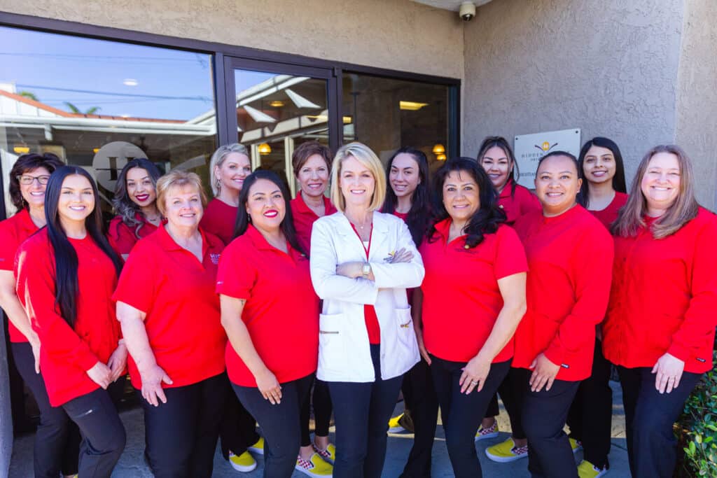 Orthodontist Dr. Fortney in her white coat, in the center of the Hidden Valley Ortho team in red