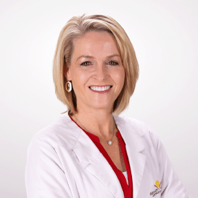 Orthodontist Dr. Fortney smiling with arms crossed in a white lab coat.