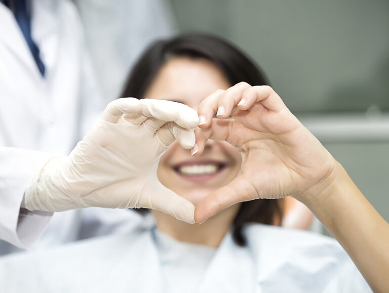Patient and their orthodontist making a heart with their hands